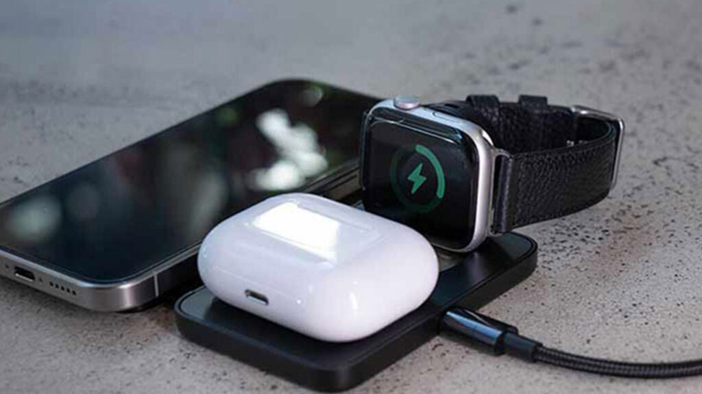 Wireless charger simultaneously charging a phone, earbuds, and smartwatch.